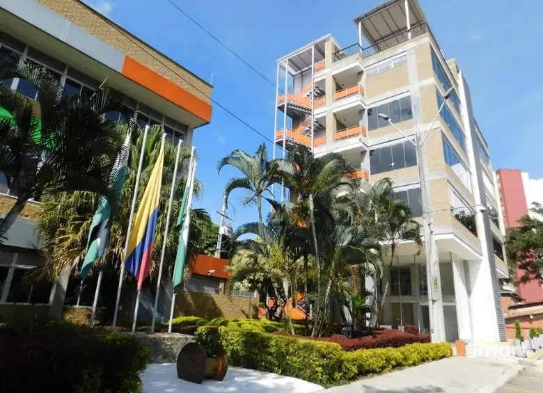 Fachada terminada del edificio, con banderas y zonas verdes de acceso.