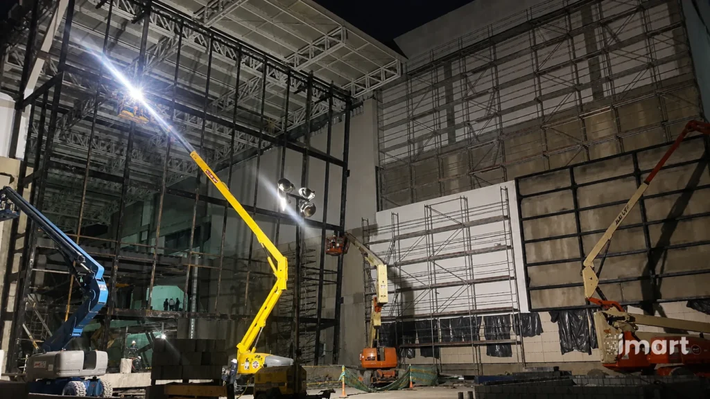 Faena nocturna con varias plataformas elevadoras trabajando en la fachada.